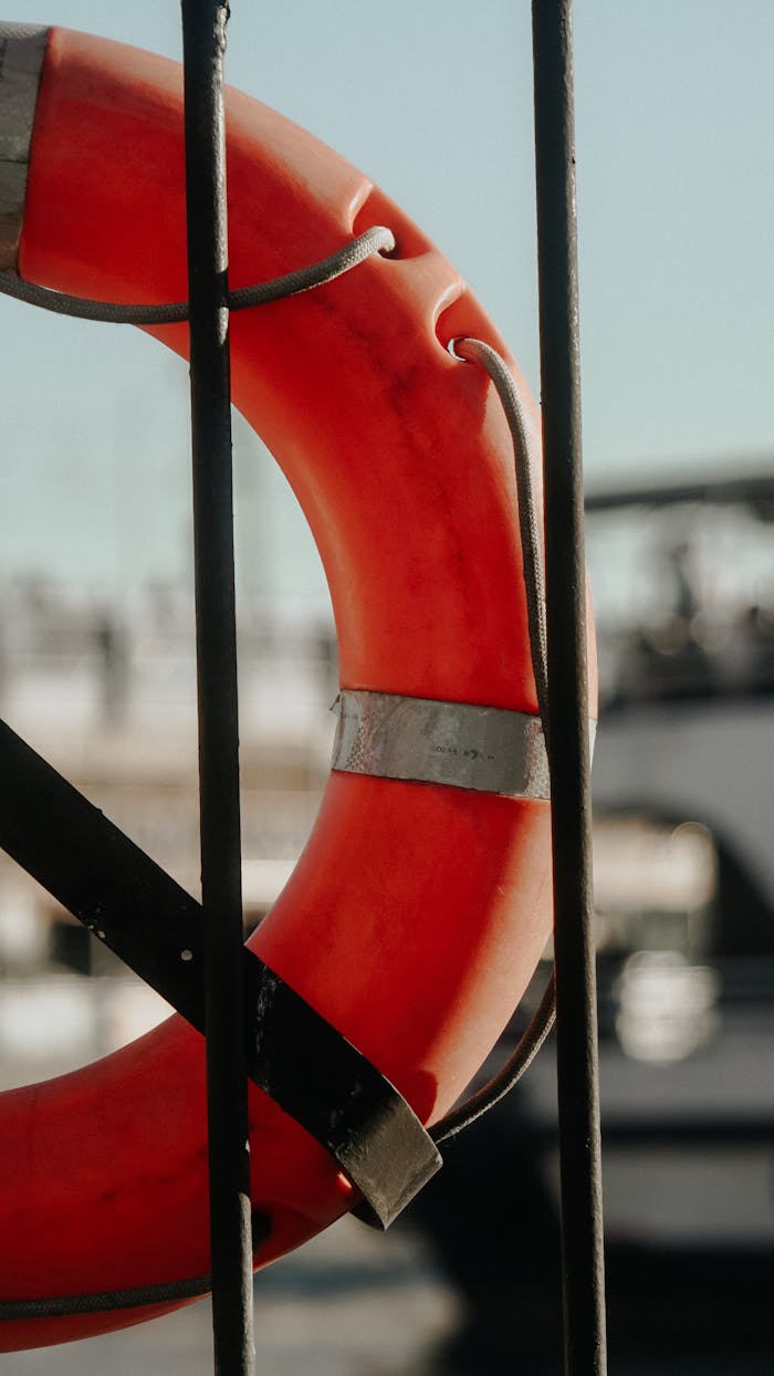 A vibrant red lifebuoy on a dock, with a blurred boat in the background.
