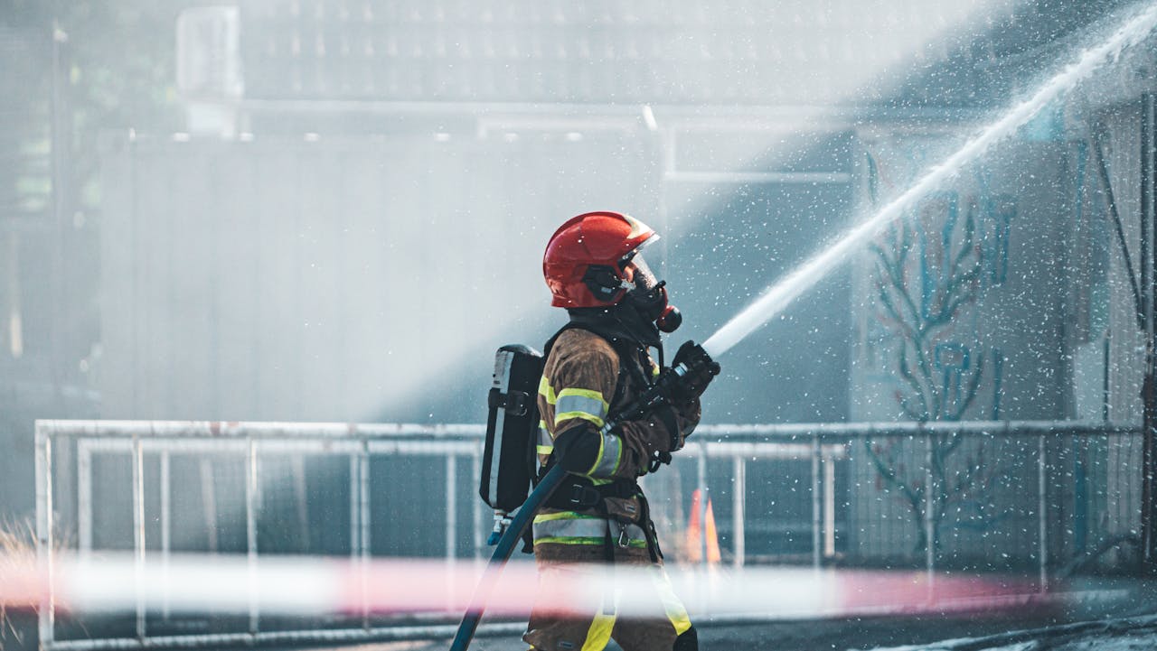 A brave firefighter operates a fire hose, wearing protective gear during a training exercise outdoors.